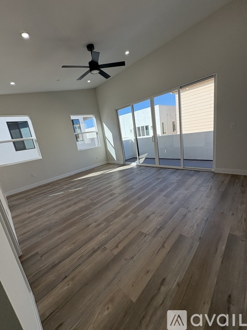 A spacious room with wooden flooring and a ceiling fan.