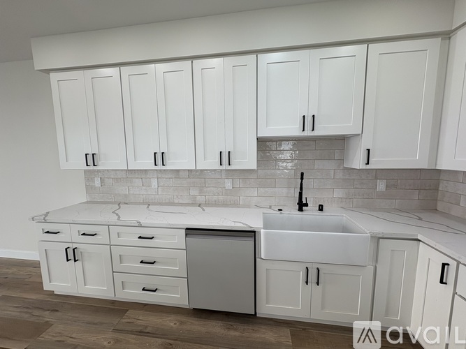 A kitchen with white cabinets and a marble countertop.