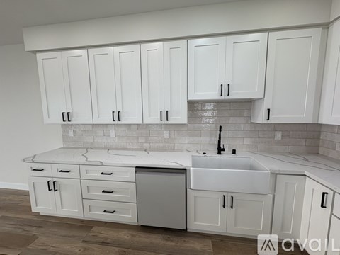 A kitchen with white cabinets and a marble countertop.