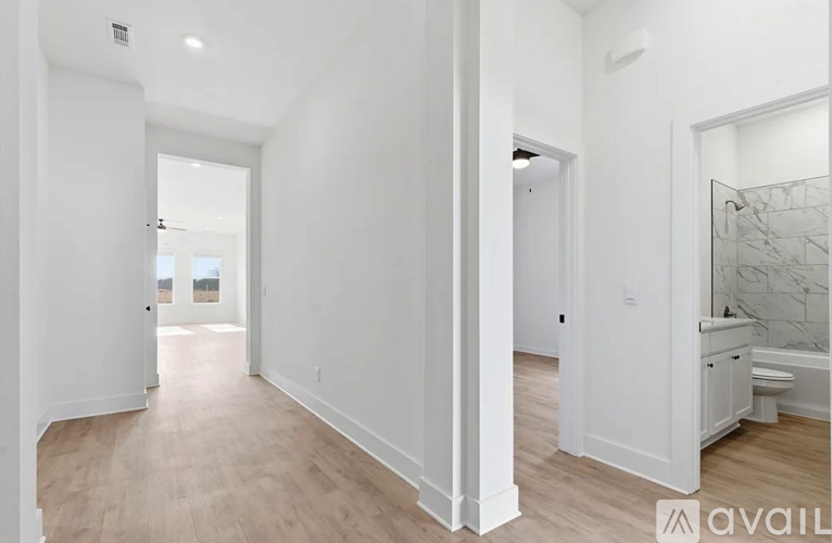 A spacious room with white walls and wooden flooring.