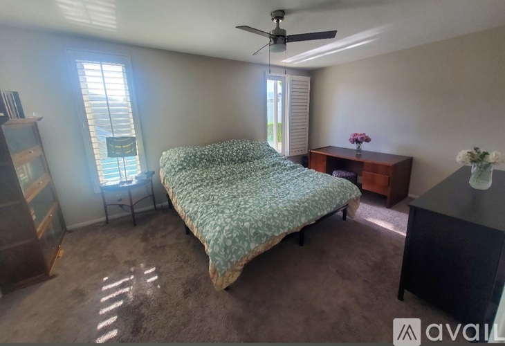 A bedroom with a bed, dresser, and window.