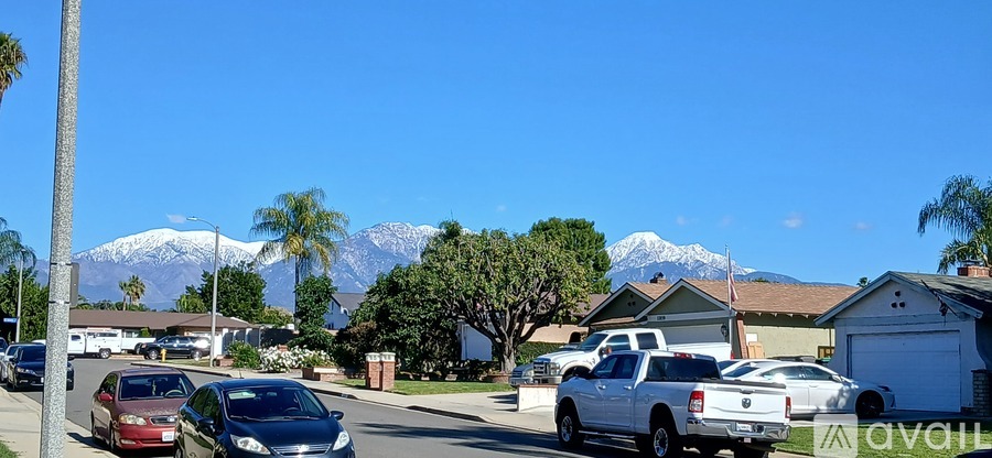 A street view with cars and houses with a mountain in the background.