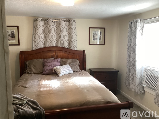A bedroom with a bed, nightstand, and two pictures on the wall.