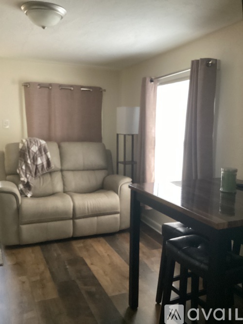 A living room with a couch, a table, and a bar stool.
