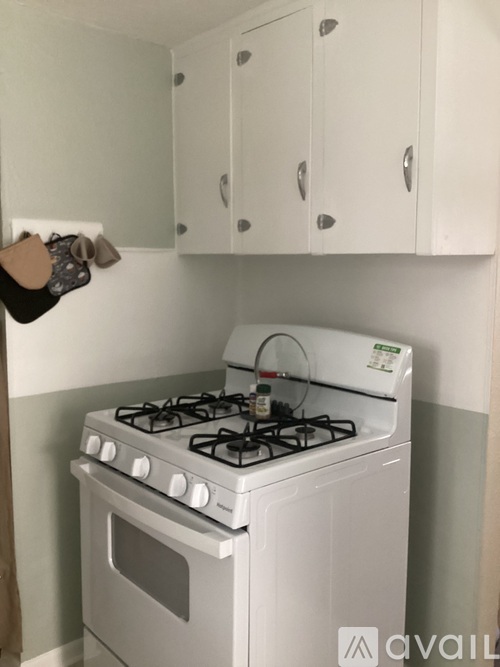 A white gas stove in a kitchen with white cabinets.
