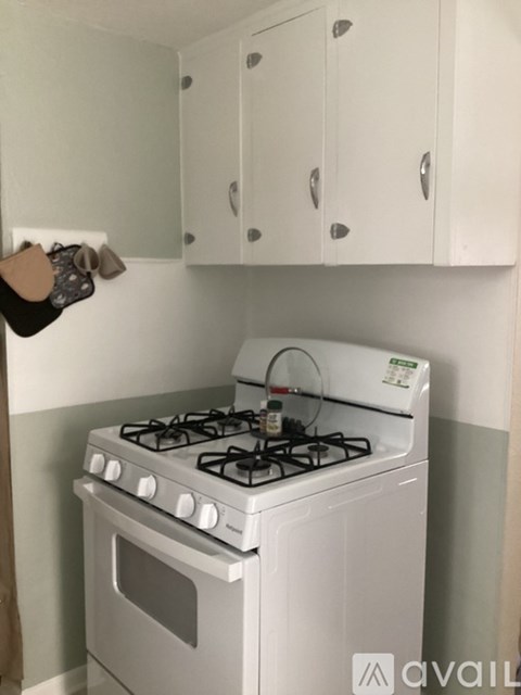 A white gas stove in a kitchen with white cabinets.