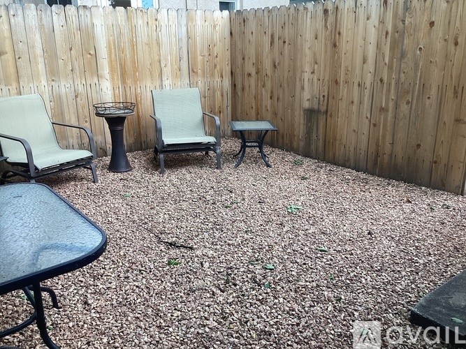 A patio with a table, chairs and a fence.