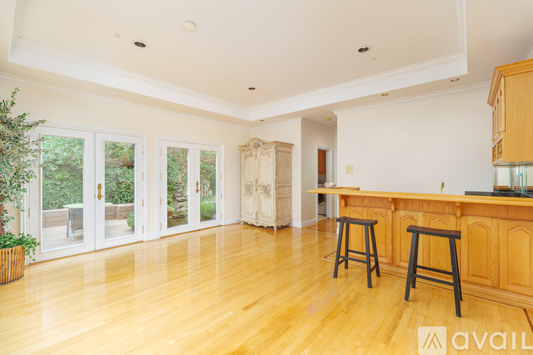 A spacious room with wooden floors and a bar area.