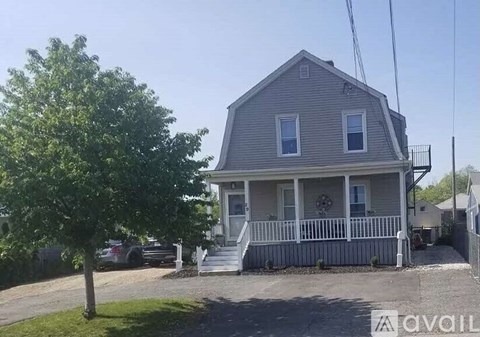 A house with a porch and a tree in front.