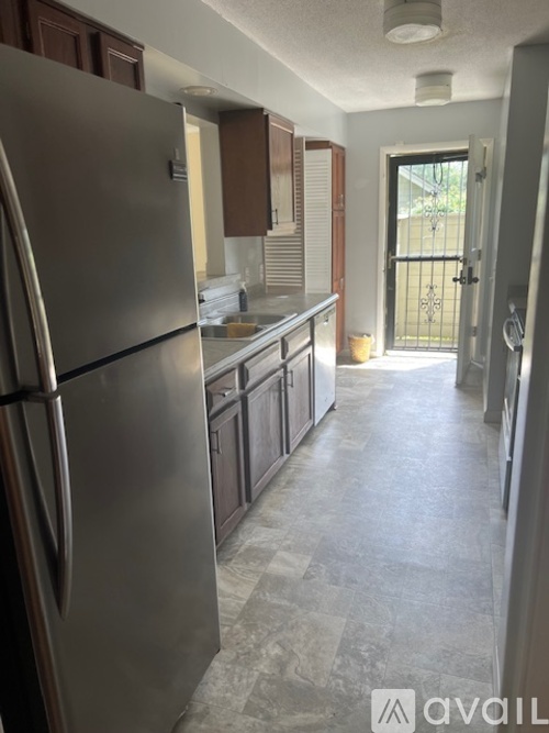 A kitchen with a stainless steel refrigerator and wooden cabinets.