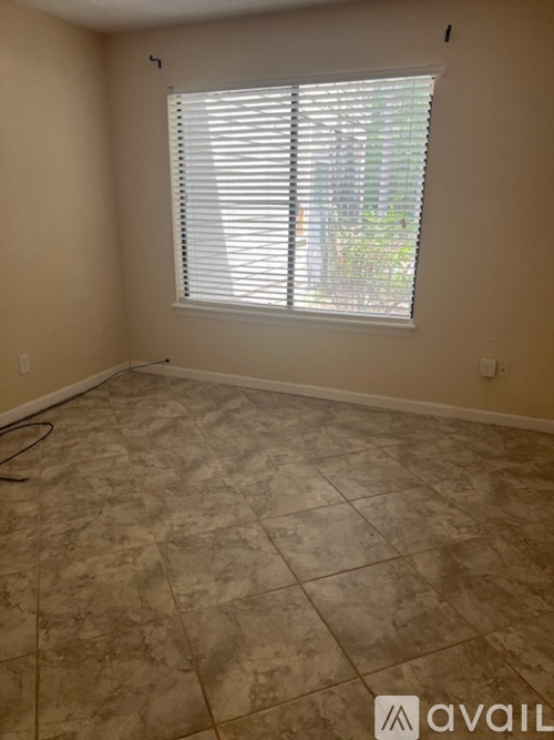 A room with a tiled floor and a window with blinds.