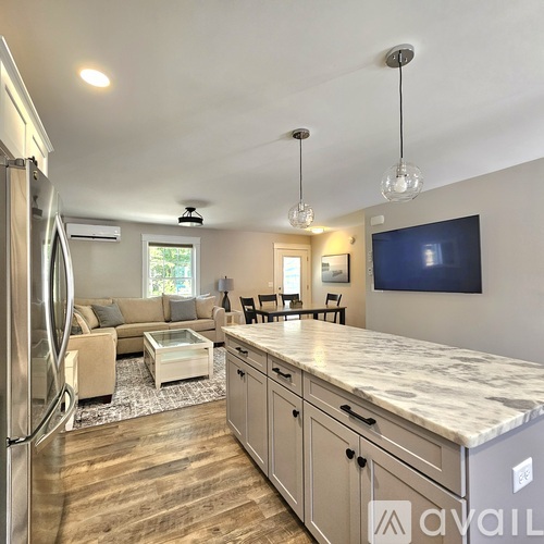 A kitchen with a marble countertop and a refrigerator on the left side.