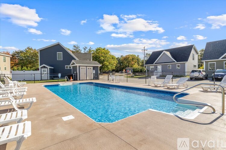 A swimming pool surrounded by lounge chairs and a house in the background.