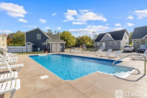 A swimming pool surrounded by lounge chairs and a house in the background.