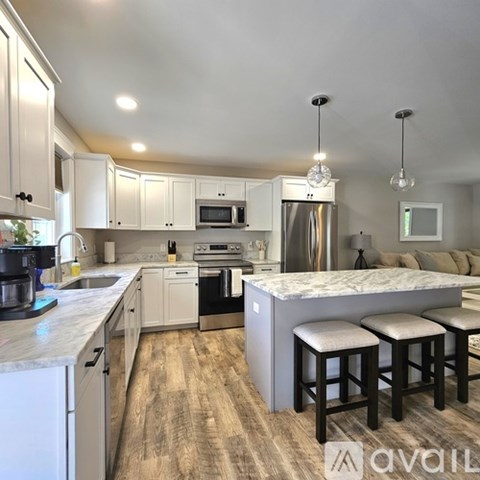 A kitchen with white cabinets and a marble island.