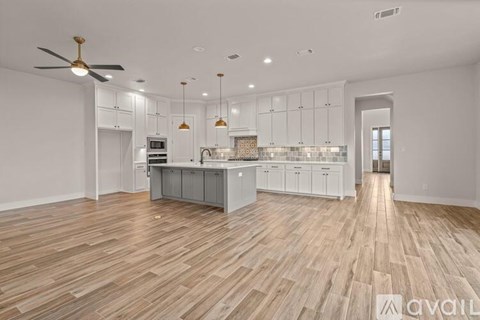 A spacious kitchen with wooden flooring and white cabinetry.