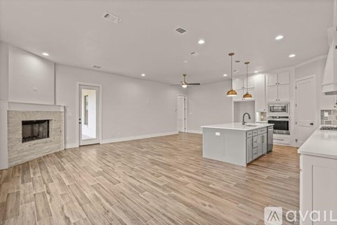 A spacious kitchen with a fireplace and wooden flooring.