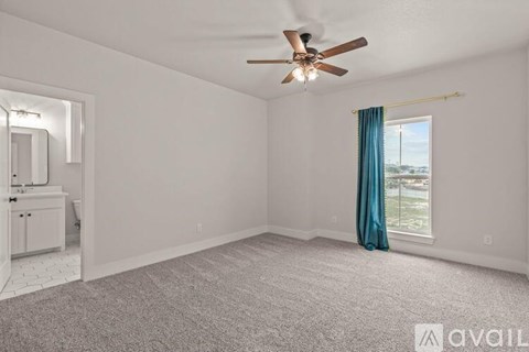 A spacious room with a ceiling fan and a window with a view of the outside.