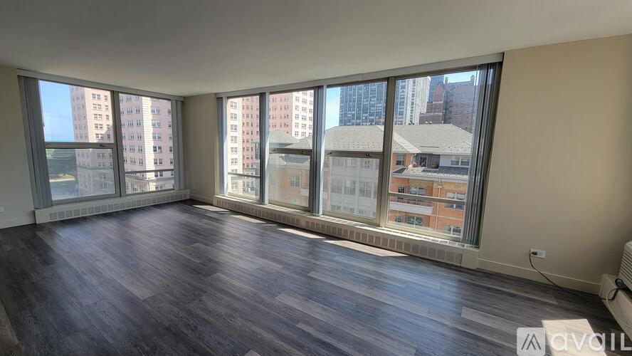 A room with wooden flooring and large windows overlooking a cityscape.