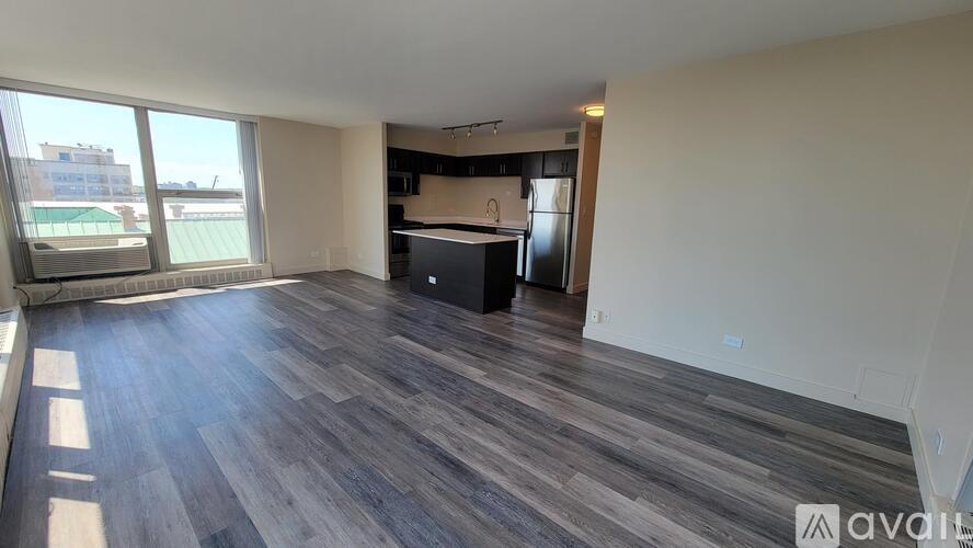 A spacious room with wooden flooring and a kitchenette in the corner.