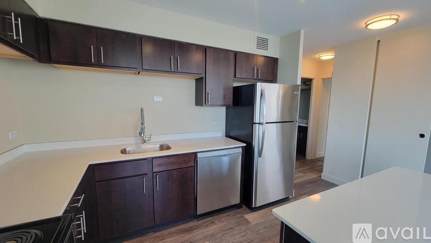 A kitchen with dark brown cabinets and a stainless steel refrigerator.