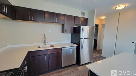 A kitchen with dark brown cabinets and a stainless steel refrigerator.