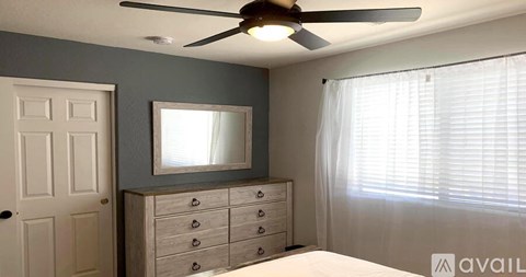 A bedroom with a bed, dresser, mirror, and window with blinds.