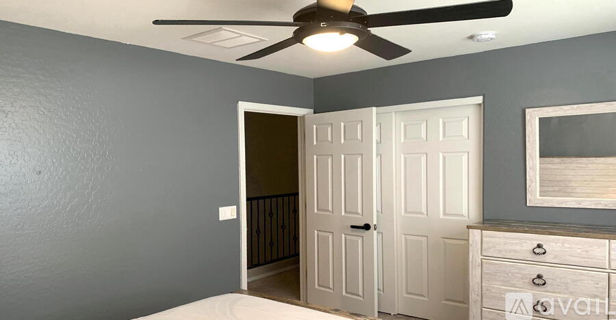 A room with a ceiling fan and a white door.
