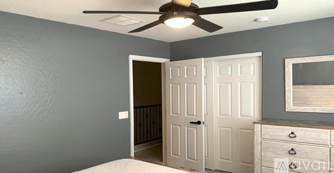A room with a ceiling fan and a white door.