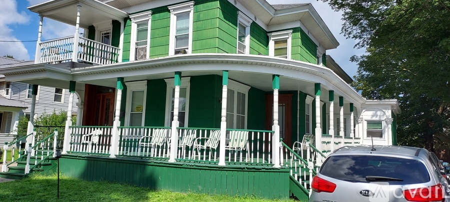 A green house with white trim and a red door.