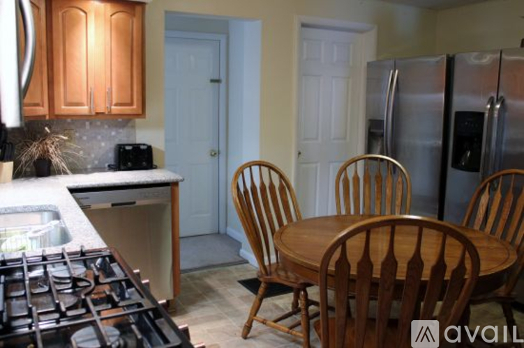 A kitchen with a stove, table and chairs.