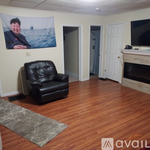 A living room with a black leather chair and a poster of a man on the wall.