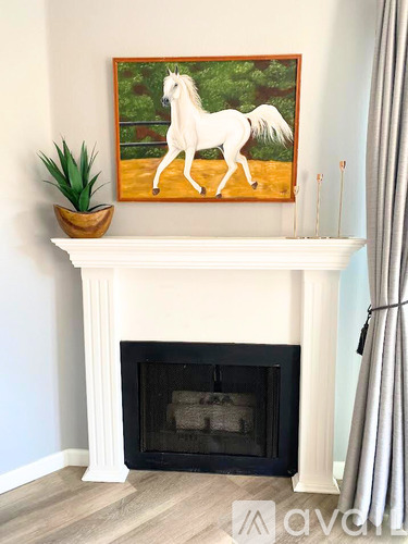 A painting of a white horse is hanging above a fireplace.