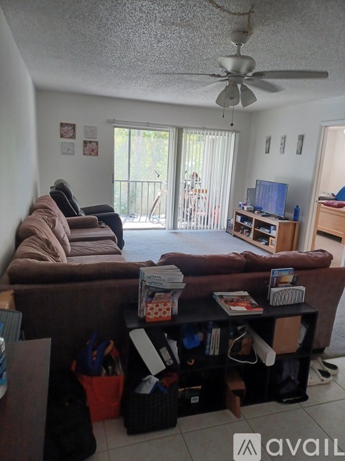 A living room with a brown couch and a ceiling fan.