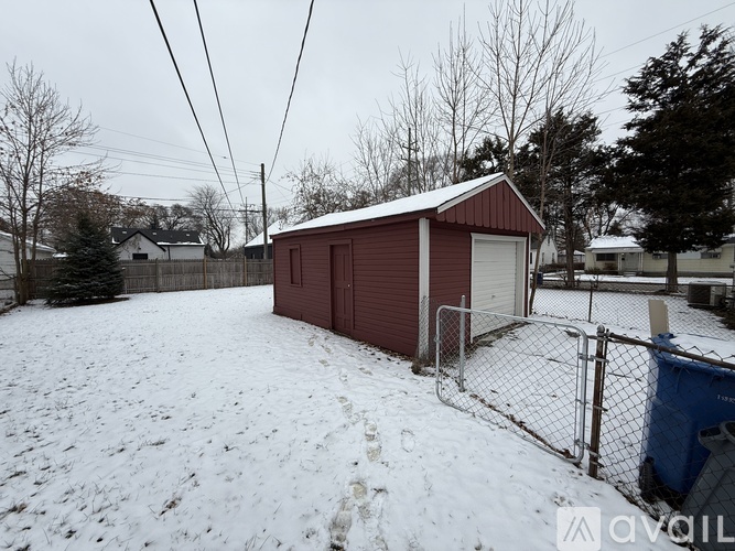 A red shed sits in a snowy backyard.