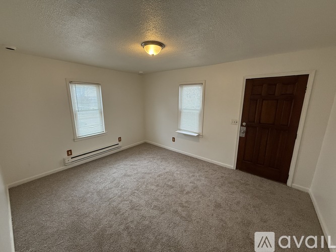A room with a carpeted floor, two windows, and a door.