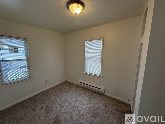 A carpeted room with a window and a ceiling light.