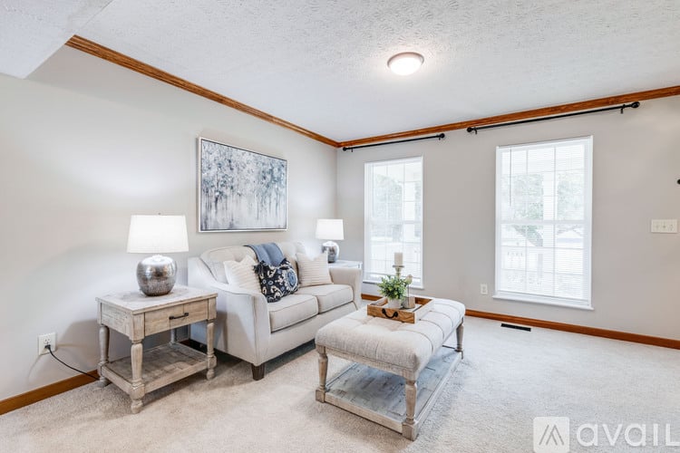A living room with a white couch, a wooden side table, and a painting on the wall.