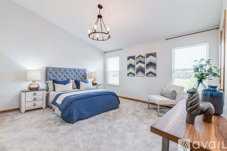 A bedroom with a blue bedspread and a white nightstand with a lamp on it.