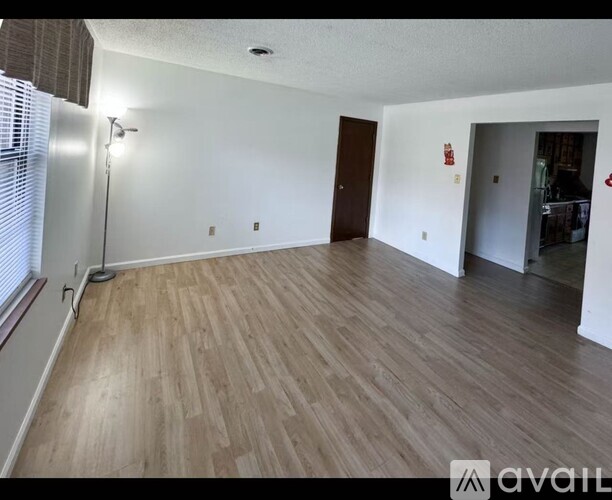 A room with wooden flooring and a window with blinds.