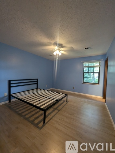 A bedroom with a bed, wooden floor, and a window.