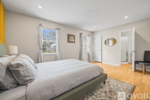 A bedroom with a large bed and a window with curtains.