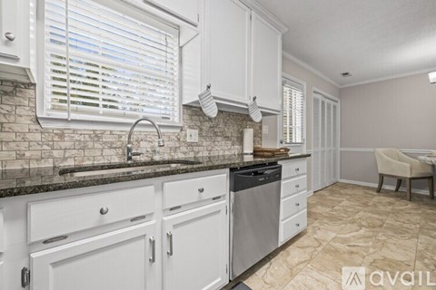A kitchen with white cabinets and a marble backsplash.
