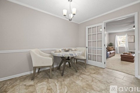 A dining room with a table set for two and a chandelier.
