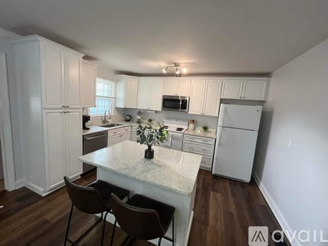 A kitchen with white cabinets and a marble countertop.