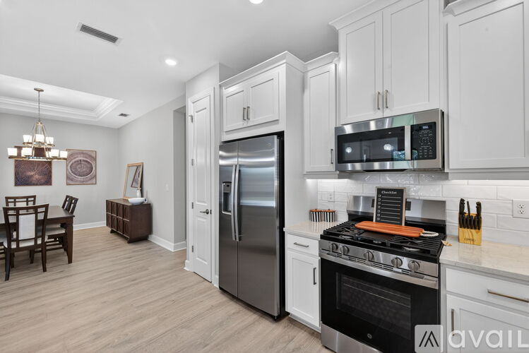 A modern kitchen with a stainless steel refrigerator and oven, and a dining table with chairs.