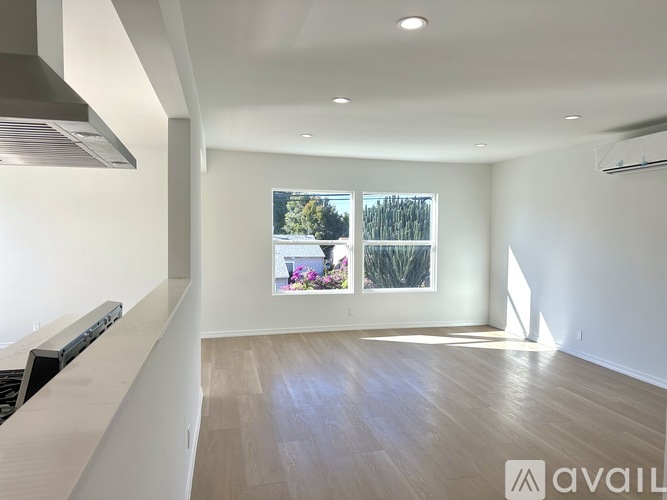 A spacious room with wooden flooring and a large window showing an outdoor view.