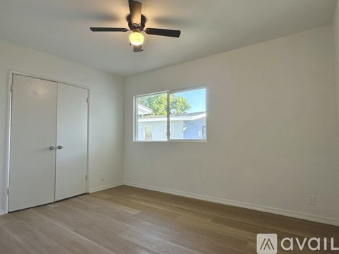 A room with a ceiling fan and a window with a view of a building outside.
