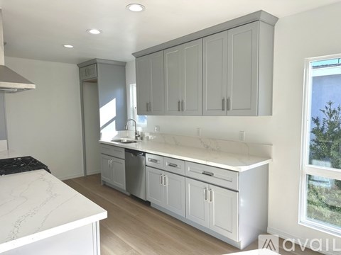 A kitchen with white countertops and grey cabinets.