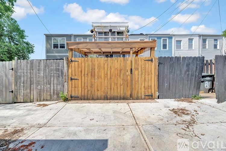 A wooden gate in front of a grey house.